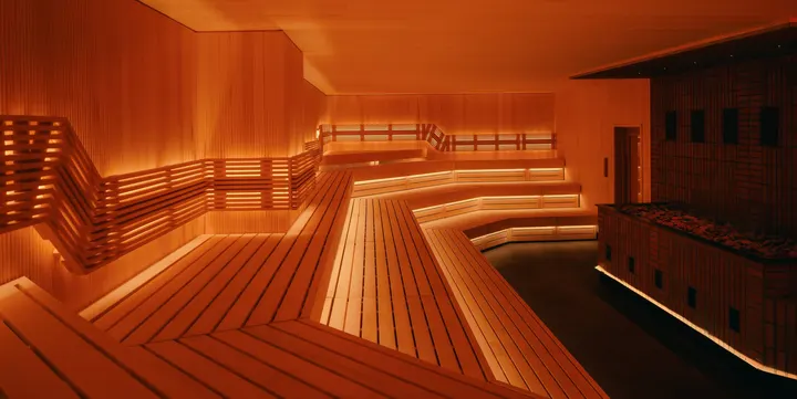 The main sauna at Othership Williamsburg: tiered wooden benches lit amber from below
