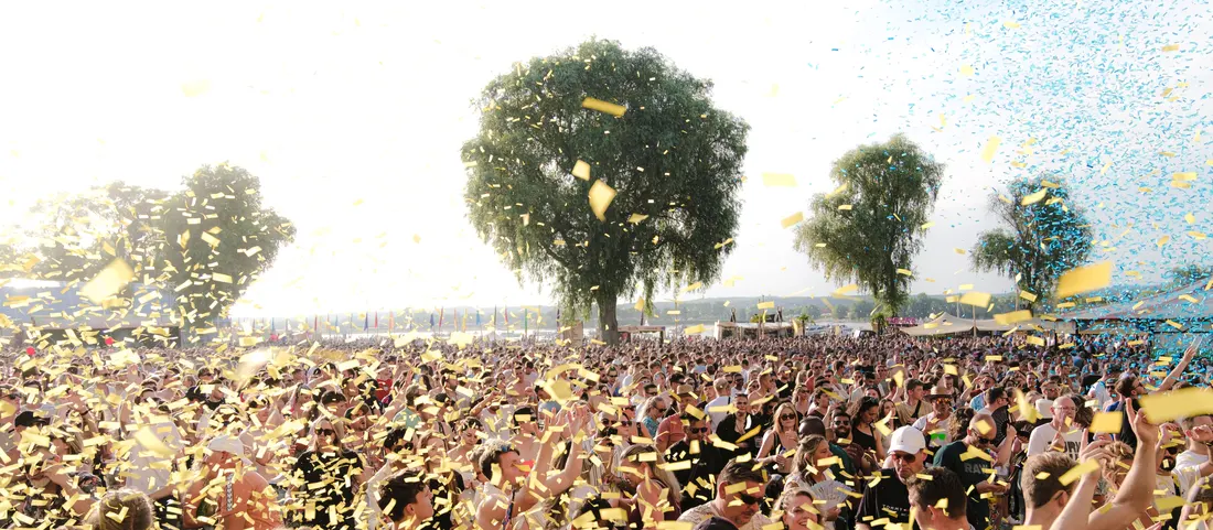 Confetti over a daytime festival crowd in a park
